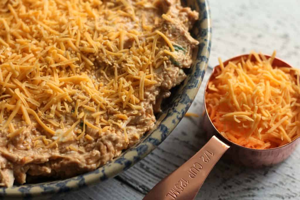 BBQ Chicken Dip Recipe | Cheese in a copper measuring cup on a rustic white table