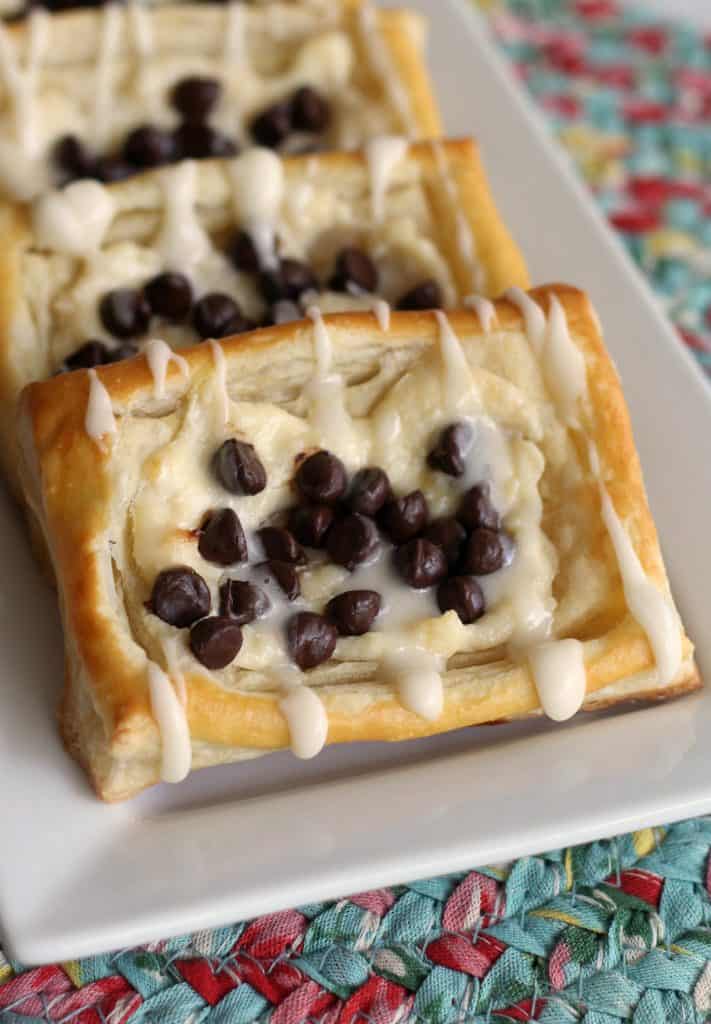 Chocolate Chip Cheese Danishes on a white plate on top of a Pioneer Woman braided place mat