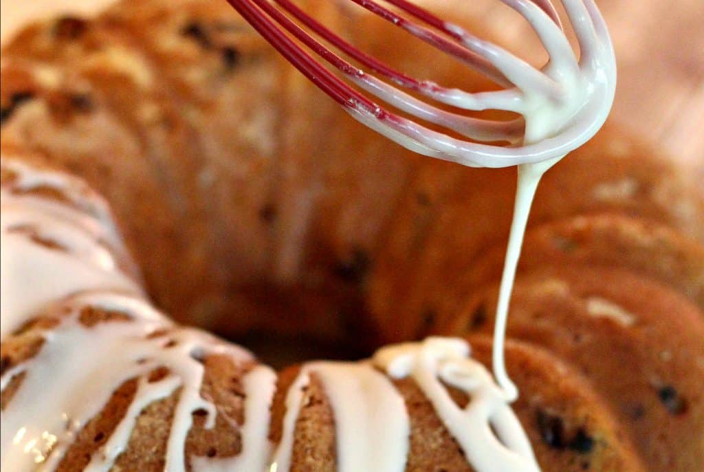 Drizzling lemon glaze onto Blueberry Yogurt Cake