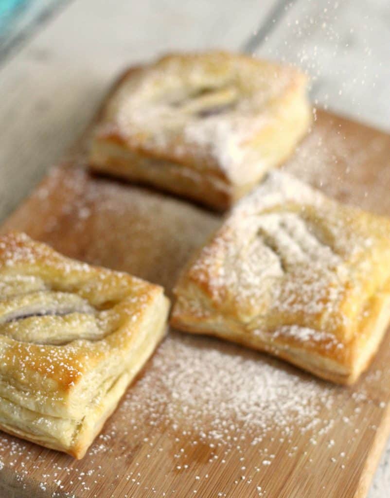 Sprinkling powdered sugar on Cuban Guava Pastries - Pastelitos de Guayaba y Queso