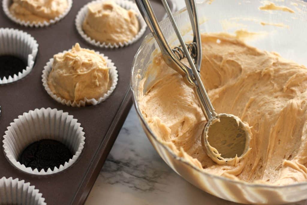 Scooping No Bake Mini Peanut Butter Cheesecakes into a muffin tin