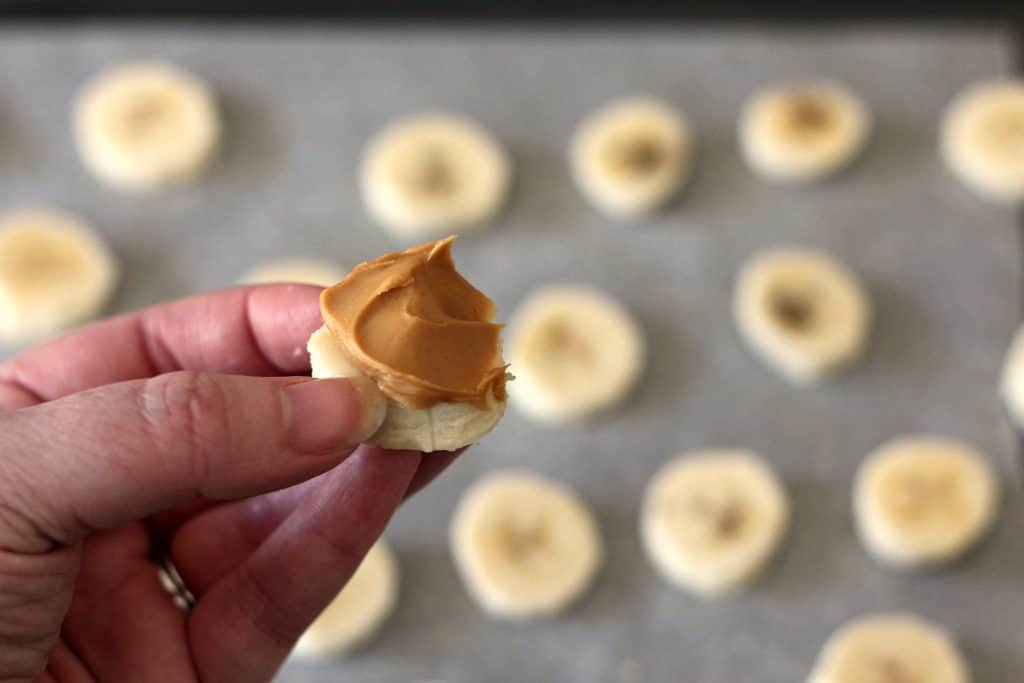 Topping banana slices with peanut butter for Chunky Monkey Peanut Butter Banana Bites