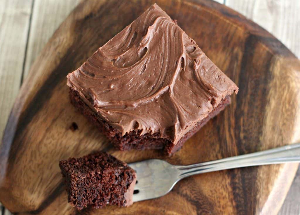 A slice of Sour Cream Chocolate Cake on a wooden platter