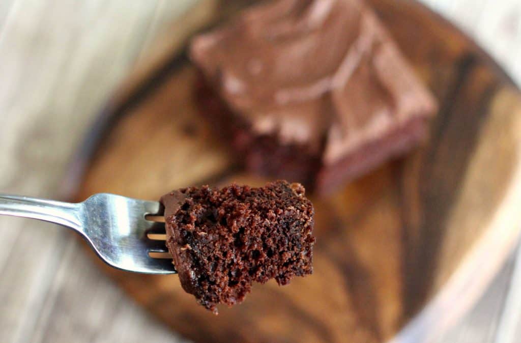 A slice of Sour Cream Chocolate Cake on a wooden platter