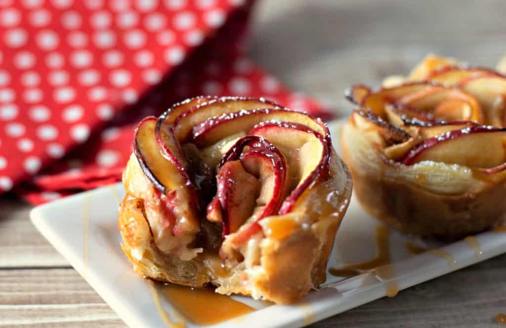 Half eaten Caramel Apple Rose Tarts on a white plate with red napkin