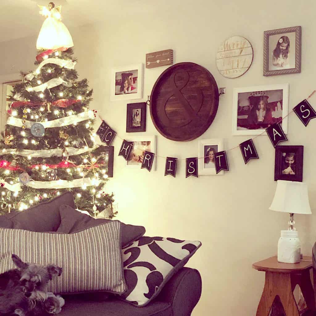 Christmas tree decorated with gold and red ribbon and an angel with sleeping Miniature Schnauzer on the couch.
