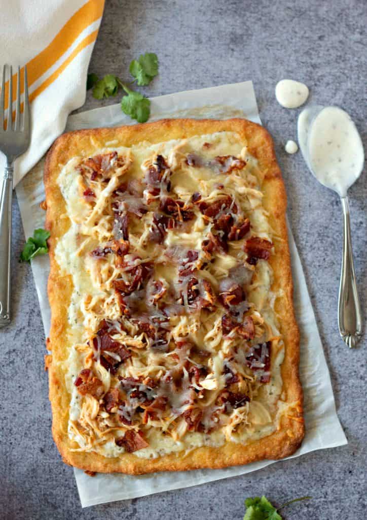 Eating low carb but missing pizza? No need to miss out! This Keto Chicken Bacon Ranch Pizza will calm your pizza craving while not messing up your eating plan. A "fat head" pizza crust loaded with shredded chicken, crispy bacon, mozzarella cheese, and creamy ranch dressing; what's not to love about this?! #Keto #KetoRecipes #KetoPizza #GlutenFree #GlutenFreePizza #GlutenFreeRecipes #LowCarb #Bacon #MomNeedsChocolate