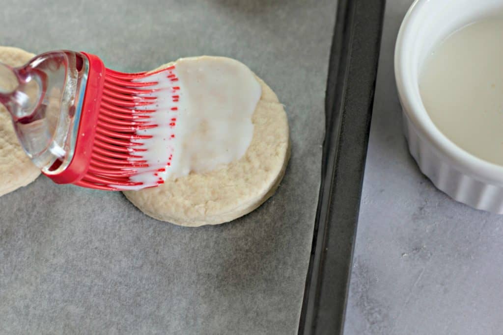 Brushing buttermilk on biscuit dough to make Flaky Buttermilk Biscuits Recipe