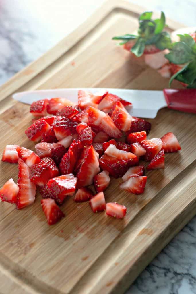 Chopping fresh strawberries to make Keto Strawberry Fluff Dessert