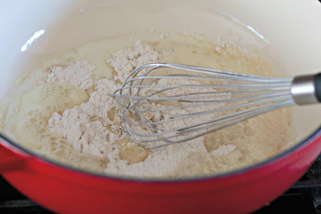 whisking together flour and butter in a red pot