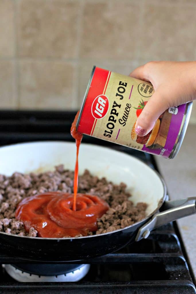 pouring sloppy joe sauce into ground beef
