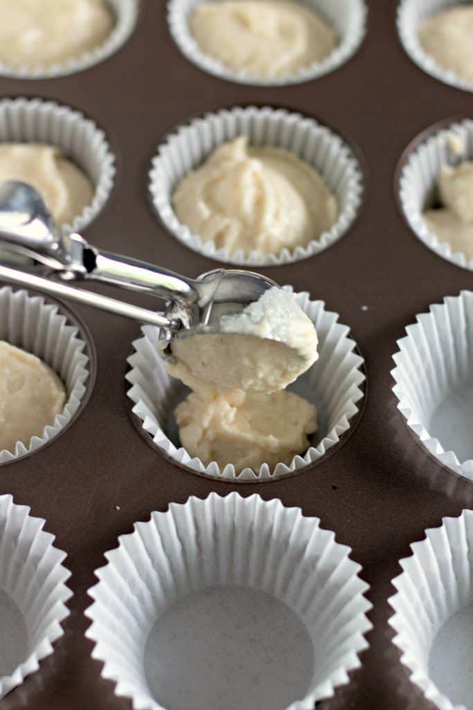 scooping cake batter into muffin cups
