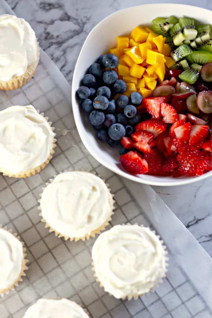 adding the fresh fruit to the top of the Fruit Pizza Cupcakes