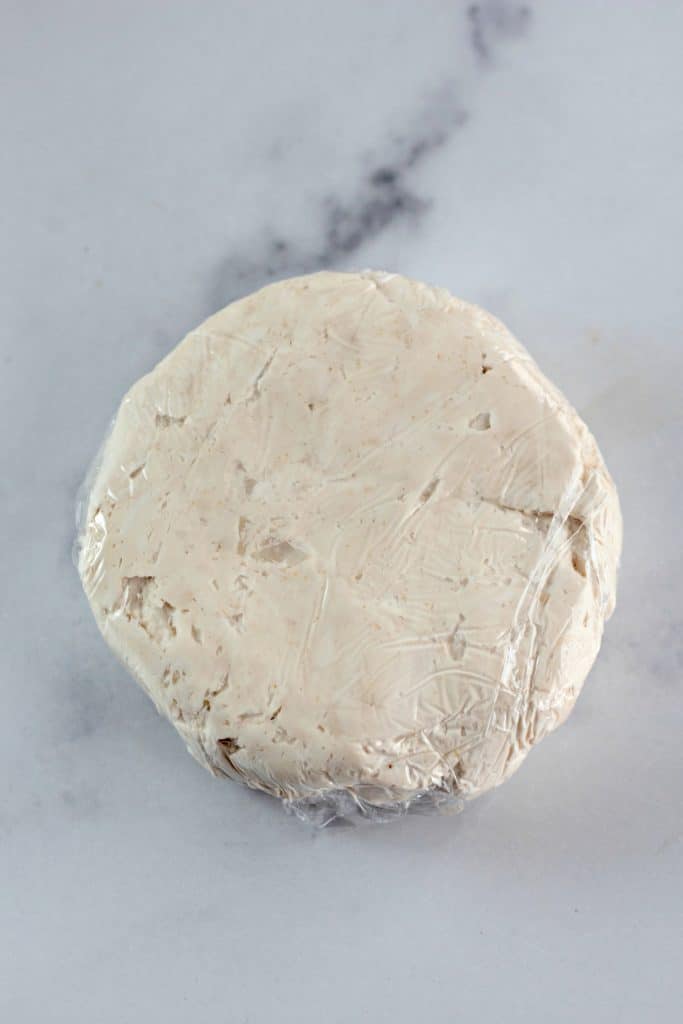 a disk of savory cream cheese in plastic wrap
