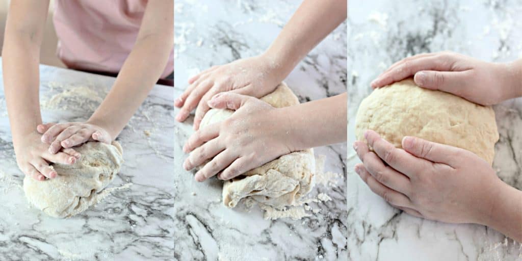 child kneading bread dough on a marble counter.