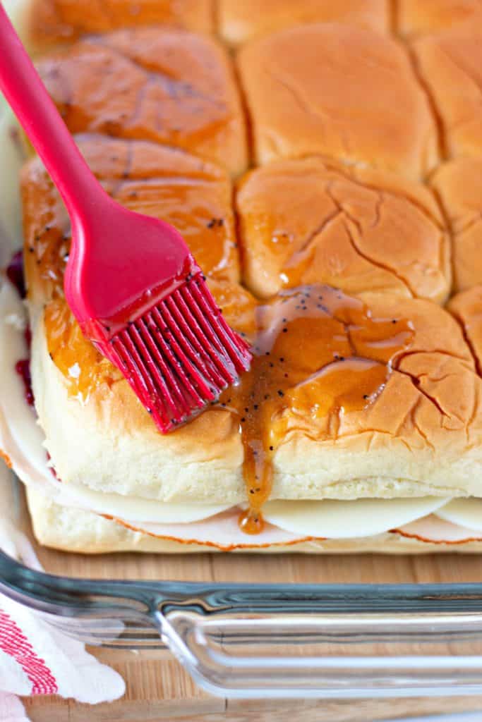 using a pastry brush to add the glaze to the sandwiches.