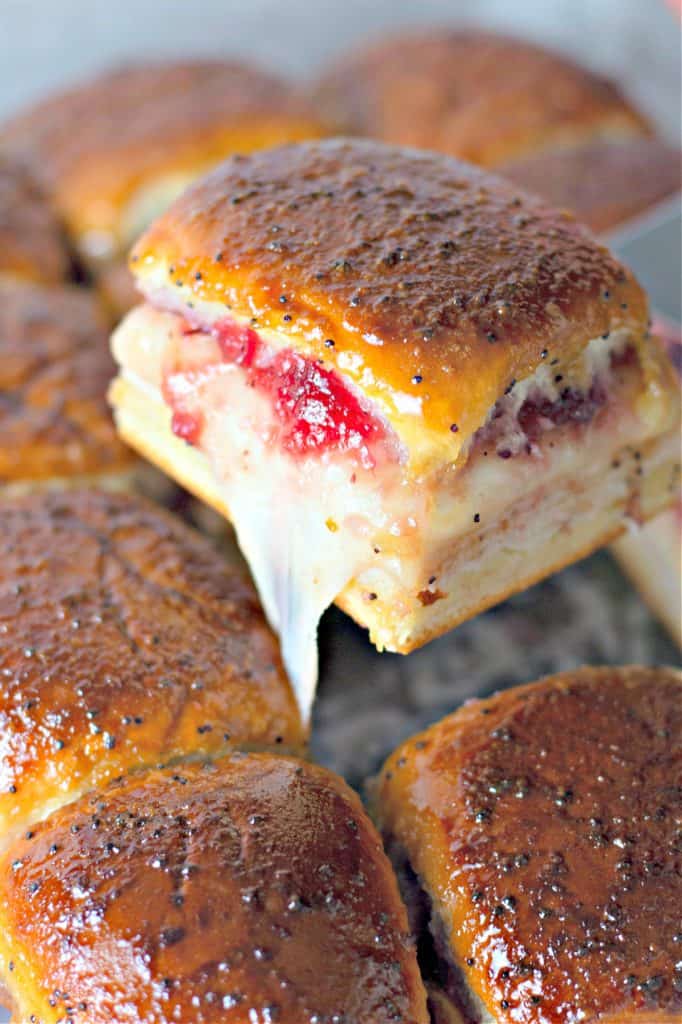 lifting a Baked Turkey Cranberry Slider from the pan with a spatula.