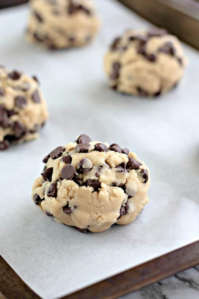 cookie dough balls on parchment paper lined baking sheets.